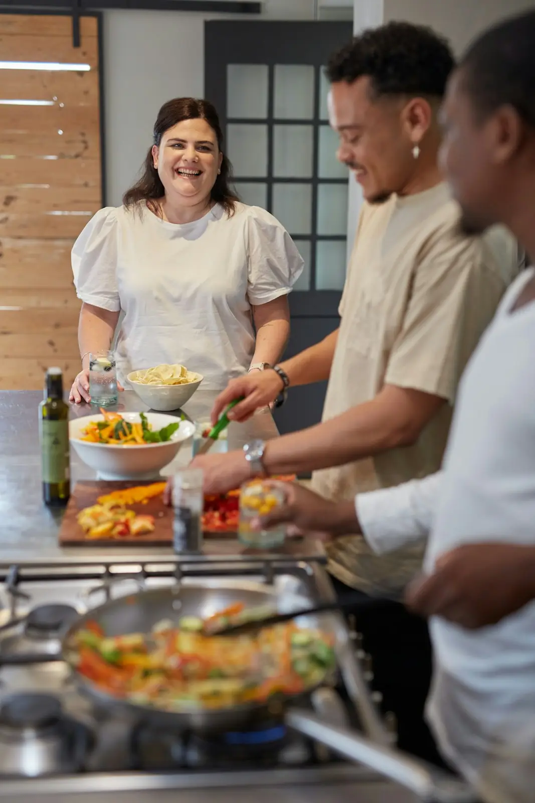 Students in aprons preparing vegetables and bowls of salad at a shared counter
