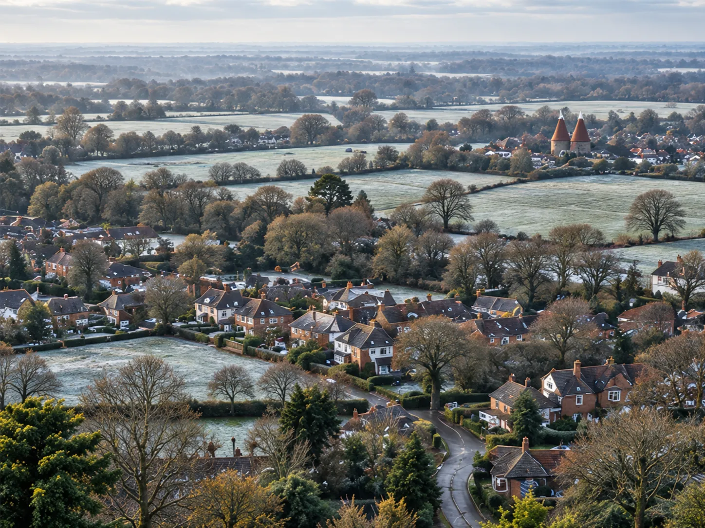 Kent villages, rooftops, hedged fields and lanes under a pale winter mist, two oast houses in the distance