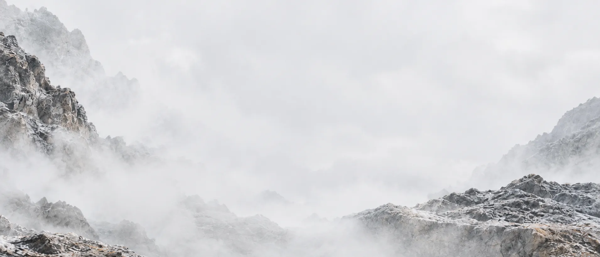 Pale rocky ridges dissolving into soft white mist