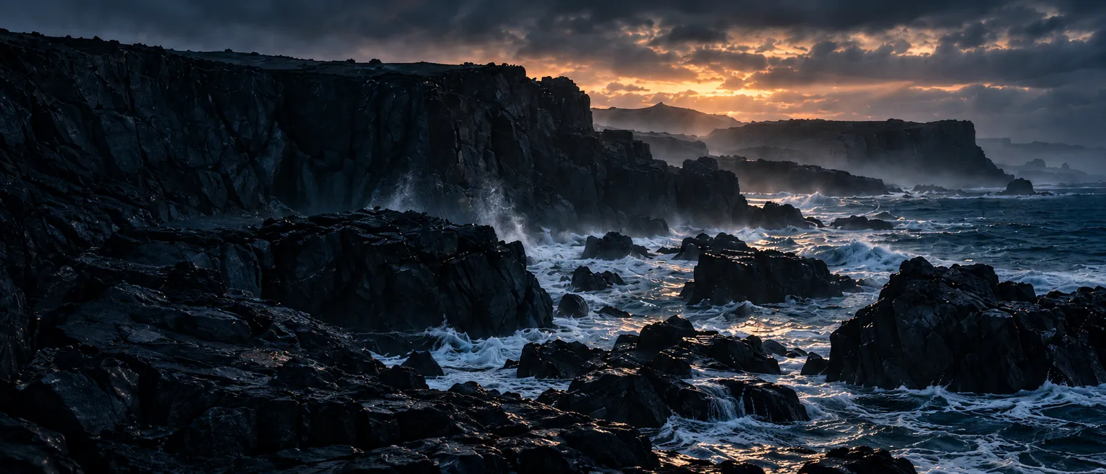 Dark basalt cliffs stepping into the sea with surf breaking white over the rocks, the first light of dawn low under heavy clouds