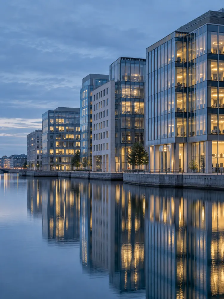 Glass office buildings on the Stockholm waterfront at blue hour, reflected in still water