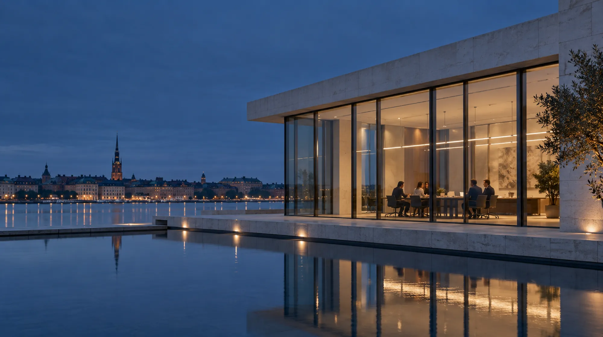 A stone-and-glass office at blue hour beside a still pool, a small team at a long table behind the lit glass