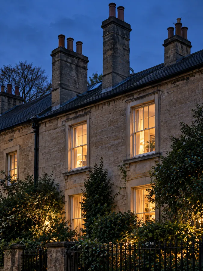 A long stone terrace with tall chimney stacks against a deep blue evening sky