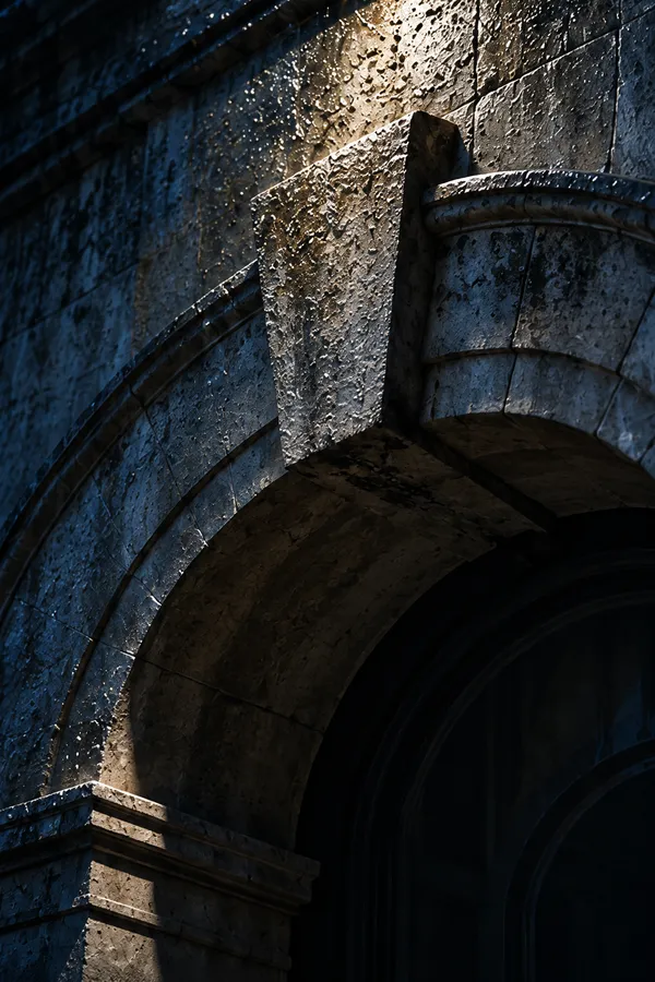 The keystone at the crown of a weathered stone arch, wet after rain and caught in moonlight