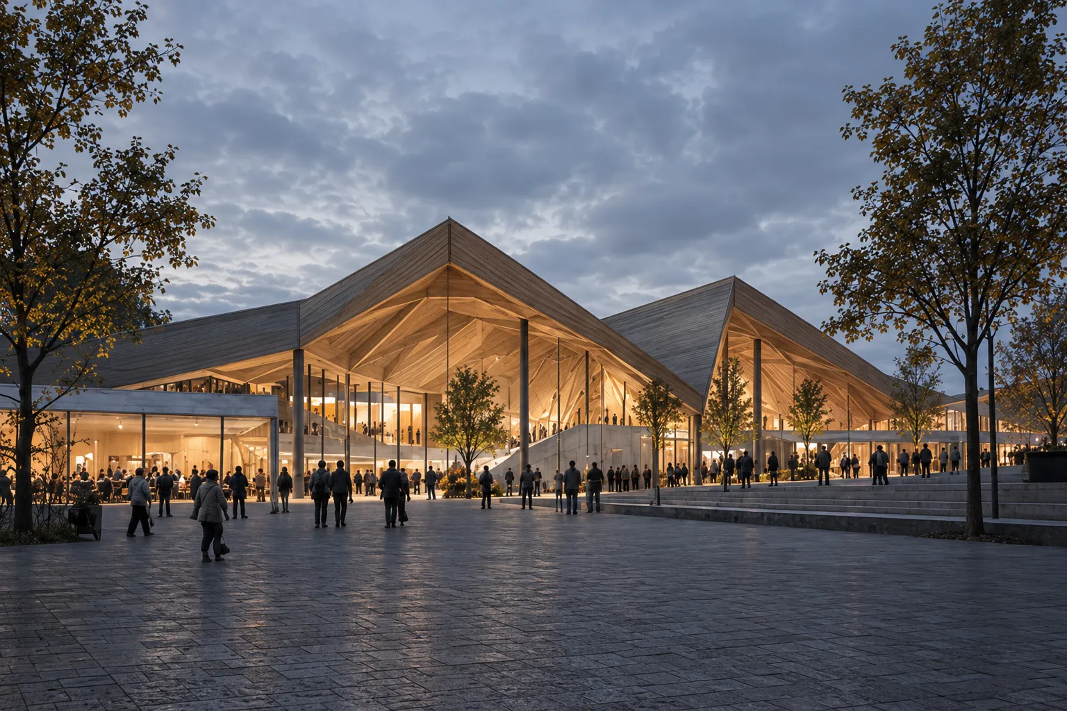 Das gefaltete Holzdach des Kulturhauses in der Dämmerung, darunter der erleuchtete Saal und Menschen auf dem Platz
