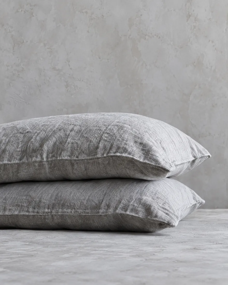Two mist-grey stonewashed linen pillowcases on stacked pillows