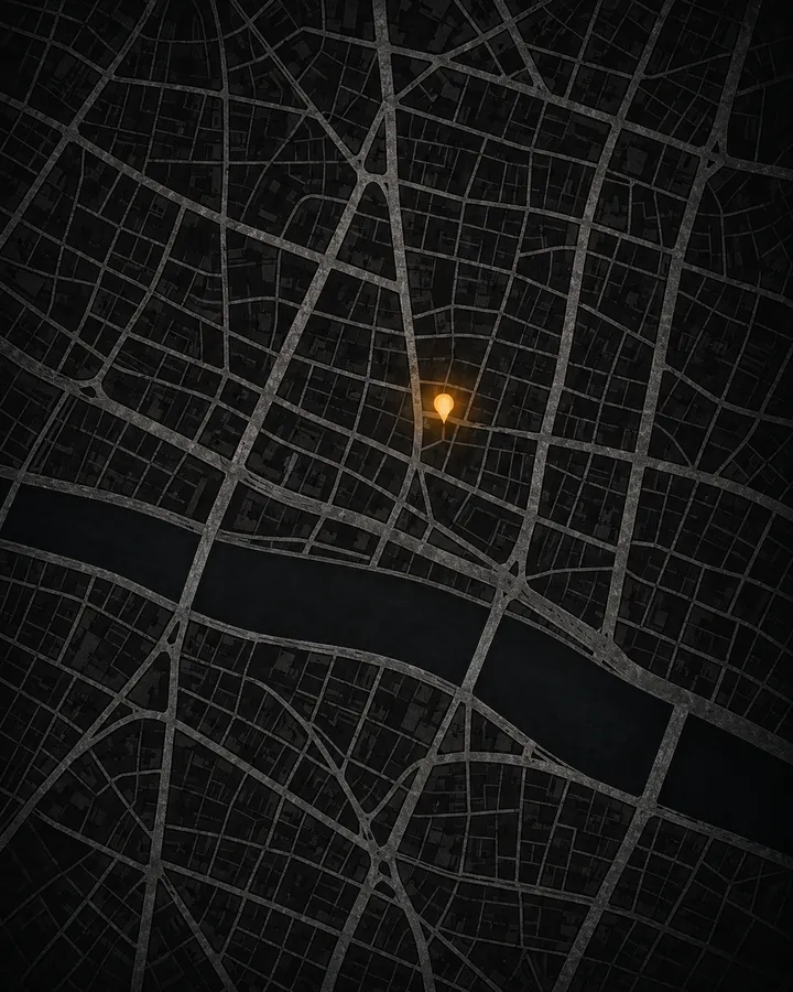 A stylised dark street map with a river along its foot and one amber light near the centre