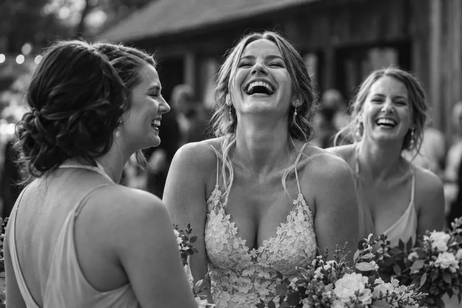 Bride laughing with her head back between two laughing bridesmaids