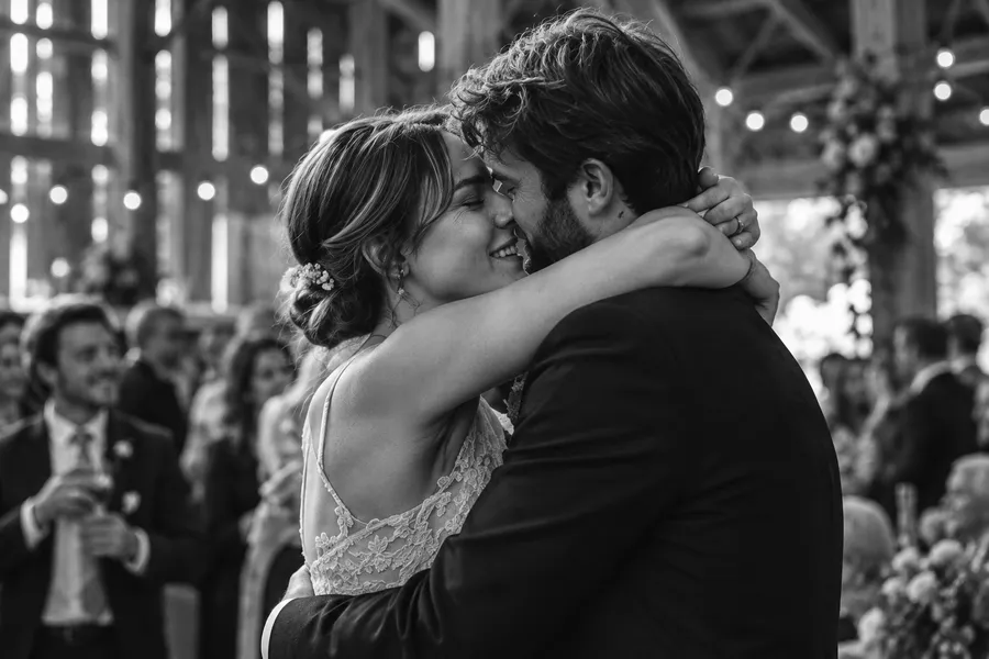 Bride hugging a man in a dark suit, her eyes closed, guests behind