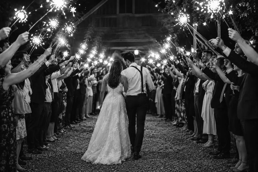 The couple walking out through a tunnel of guests holding sparklers at night