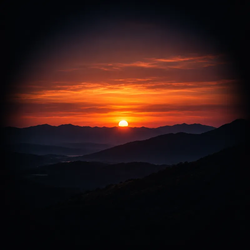 The sun just set behind layered mountain ridges, an orange glow under a dark sky