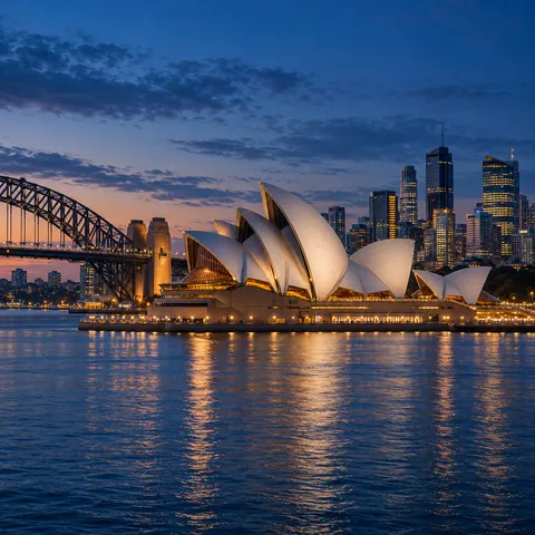 The Sydney Opera House sails on the harbour at dusk, reflected in calm water