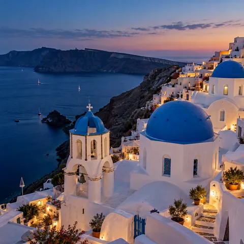 White Santorini houses and blue domes above the caldera at dusk