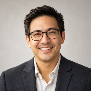 Portrait of James Carter smiling, with short dark hair and glasses, in a dark blazer