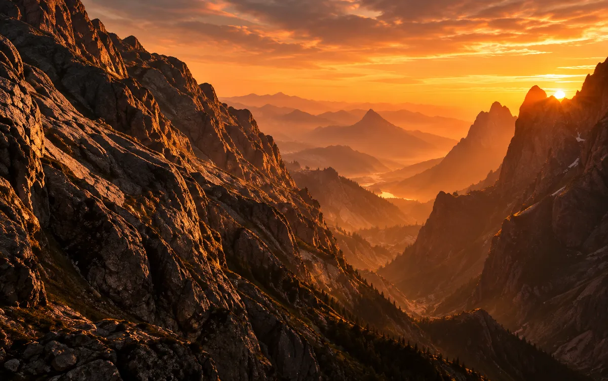 Jagged mountain ridges and a deep canyon glowing orange at sunset