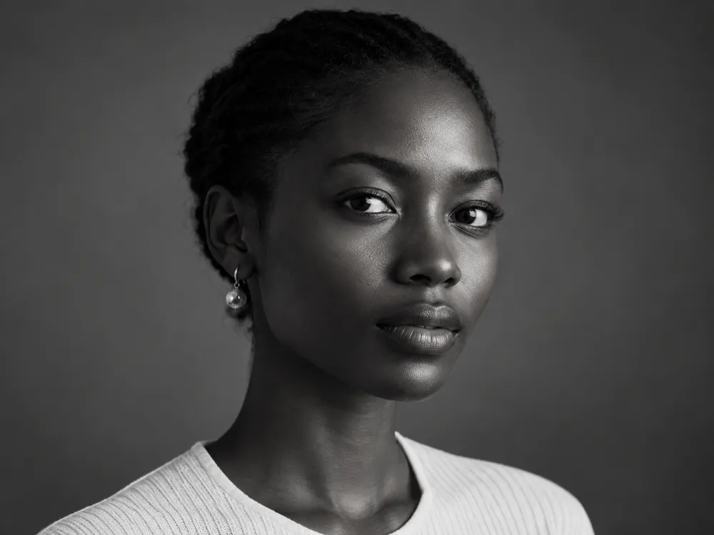 Black and white portrait of Inès Okafor, a woman with her hair pulled back, looking straight ahead