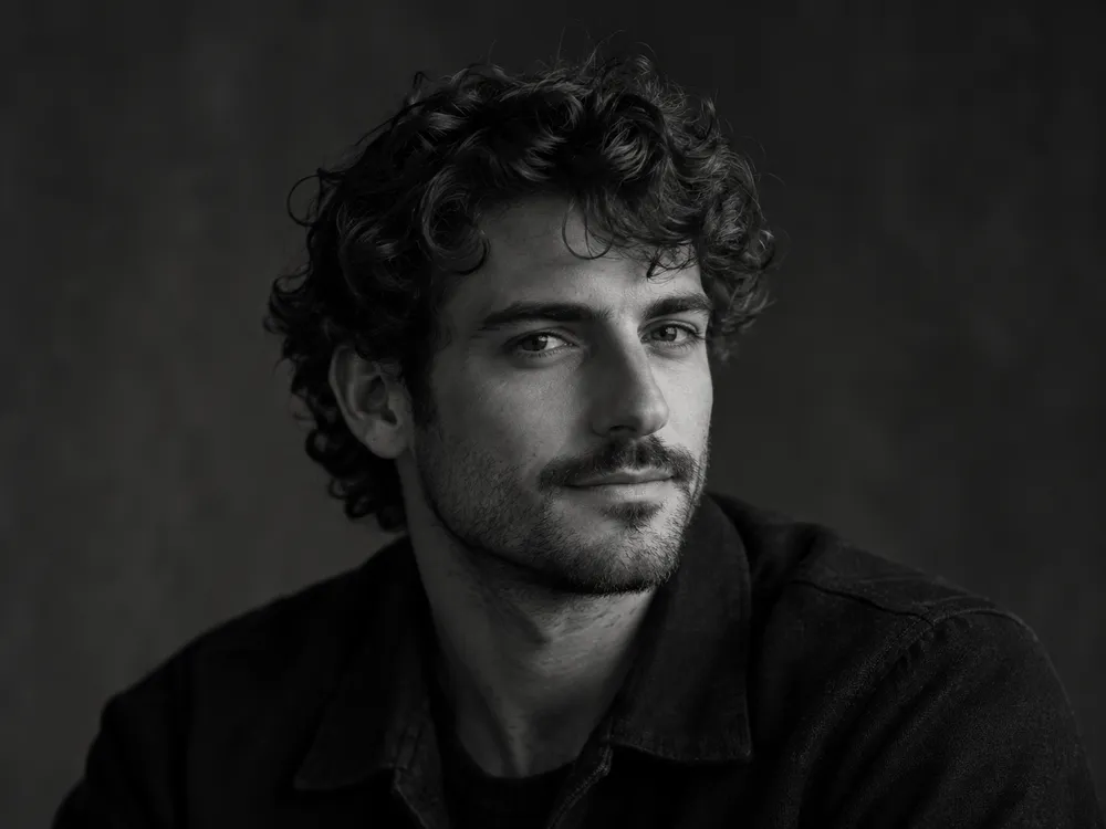 Black and white portrait of Theo Marchetti, a man with short curly hair and stubble in a dark jacket