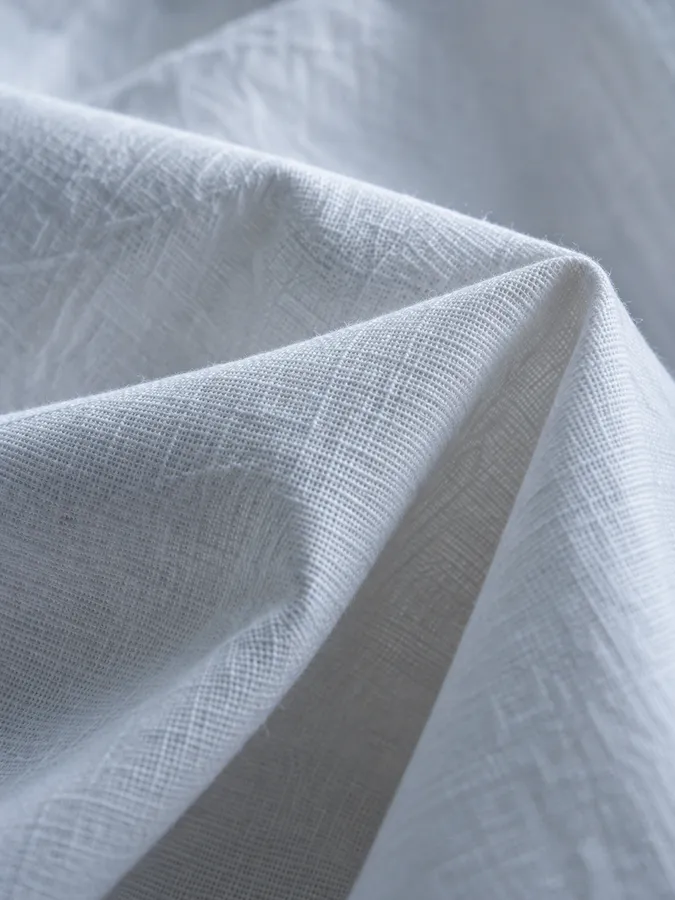 A close-up of white cotton poplin folded in soft light