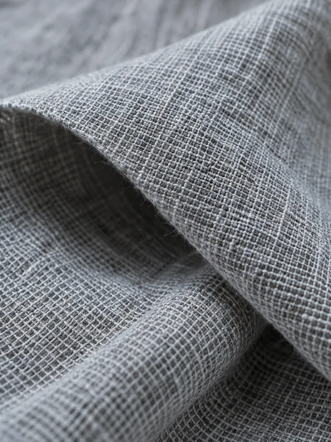 A close-up of folded grey linen with an open weave