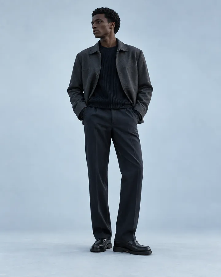 A man in a soft charcoal jacket over a dark knit
