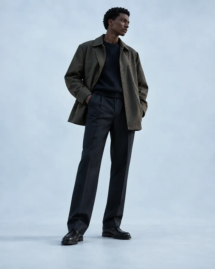 A man in a muted olive field coat over a dark knit
